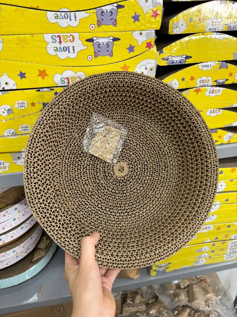 Bàn cào móng mèo bằng carton gợn sóng dạng tròn, cầm trên tay trong kho
