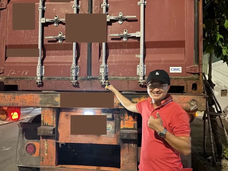 Mark Ton đứng cạnh container vừa đóng hàng, giơ ngón tay cái